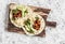 Spicy beans, avocado and green chile sauce tortilla on a rustic cutting board on a light background.