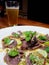 This is spicy beef salad in white plate and a glass of beer above wooden