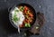 Spicy beef with vegetables and rice in a cast iron skillet on a dark background, top view.