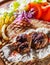 Spicy bifteki, frikadelle or frikkadel meatballs with minced beef and lamb with pita bread, tzatziki dip, vegetables salad and Fre