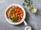 Spicy braised lima beans in tomato sauce and ciabatta toast on a grey background, top view. Delicious vegetarian lunch