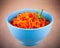 Spicy carrot salad in blue bowl on brown background