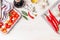 Spicy cuisine with variety of fresh spices and ingredients on white wooden background, top view, border