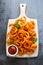 Spicy Curly Fries with ketchup on white wooden board