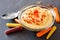 Spicy hummus dip and baby rainbow carrots close-up on slate