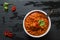 Spicy lentil and meatball soup with parsley. White bowl on black stone background, top view