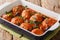 Spicy meatballs cooked with wild mushrooms in tomato sauce close-up in a baking dish. horizontal