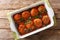 Spicy meatballs cooked with wild mushrooms in tomato sauce close-up in a baking dish. Horizontal top view