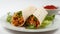 Spicy mexican chicken fajita wraps on a white plate with side serving of spicy salsa, and fresh salad. Photo has short depth of