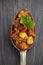 Spicy Mexican dish chili con carne in a spoon, conceptual photo