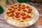 Spicy pepperoni pizza with salami sausages, chili pepper slices on wooden board, Christmas new year decoration on background