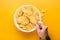 Spicy potato crisps in a bowl on yellow background