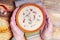 Spicy soup with sour cream, bread and spices on burned wooden table. Traditional rural dinner. Old woman hands holds clay bowl