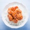 Spicy sweet and sour chicken with sesame and rice on blue wooden background top view