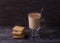Spicy warming tea with milk in glass cup with cinnamon, gingerbread cookie on wooden table