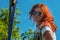Spider woman. A middle-aged woman poses with orange hair and sunglasses next to the cobweb.