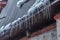 Spiked icicles at the edge of pitched gray roof with clumps of snow in winter