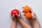 Spiky red massage needle ball in child hands and two oranges balls in woman hand on white background