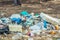 Spilled recycling garbage in park forest. Empty used dirty waste plastic bottles and carton paper boxes. Environmental