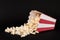 Spilled Red and White Popcorn Box on Black Background. Movie and Food Concept