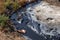Spilled streams of liquid crude oil flow down drainage ditch into public body of water. Environmental disaster Oil pollution of