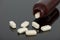 Spilled tablets on reflective counter from a fallen bottle