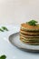 Spinach and banana pancakes and green leaves on a gray plate on a gray background.