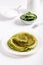 Spinach pancakes on white plate. Stack of green crepes on white background