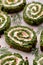 Spinach roulade stuffed with cream cheese and smoked salmon sliced on a white ceramic dish, close-up