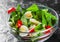 Spinach salad with eggs, pepper and tomatoes in glass bowl on dark