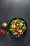 Spinach salad with fresh cucumbers, tomato, onion, pomegranate, sesame seeds and cashew nuts on black background. Healthy vegan fo
