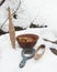 Spindle, mirror and clay plate with bread in the snow. Still life.