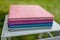 Spines of books, albums, notebooks or photobooks with grey, turquoise, purple and pink leather covers lying on white wooden box