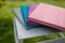 Spines of books, albums, notebooks or photobooks with grey, turquoise, purple and pink leather covers lying on white wooden box