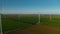 Spinning wind towers generating energy in fields. Drone view of wind turbines.