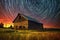 spiraling star trails above a peaceful rural barn