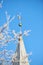 Spire of the church above the trees. Church spires against the cloudy sky in a blue sky. Close up of a spire in an