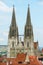 Spires of the St. Peter Cathedral above historical buildings roofs over the blue sky in Regensburg, Germany.