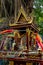 A spirit house with an old banyan tree behind it.