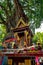 A spirit house with an old banyan tree behind it.