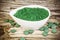 Spirulina,chlorella supplement powder and pills in white bowl and on wood