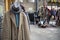 Spitalfields flea market. Woolen cashmere men`s coat with felt hat on the background of rows with clothes for sale