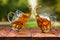 Splash of beer in two glasses on wooden table against park