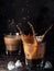 Splash in a glass with ice coffee on a dark background. Refreshing iced cappuccino drink with ice cubes. A wave of cold drink.