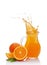 Splash in glass jug of juice with falling slice of orange
