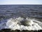 A splash of sea water on a stone pier with lots of foam and spray on a Sunny day against a flat horizon