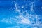 Splashes of clear blue fresh water in pool, air bubbles, water drops, sea wave on blue background with sunny reflections