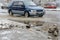 The splashes water from under the wheels of a vehicle moving through spring dirty puddles from melted snow. Flood waters