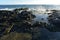 Splashing wave of turbulent sea reflected in calm water of rocky tidal pool