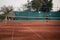 Split Croatia September 2020 Wide shot of a dirt orange tennis field, man on the other side spinning to hit the ball which is